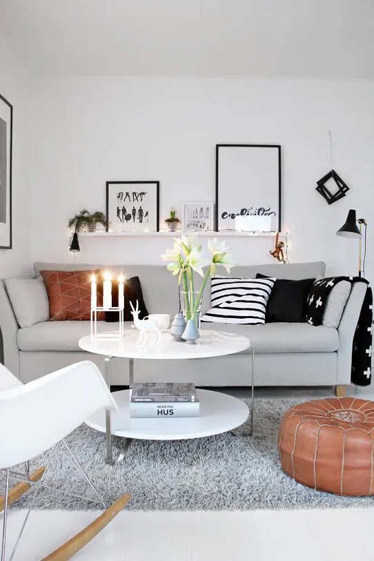 A small Scandinavian living room in neutral colors with black accents, printed pillows, and fairy lights and lamps