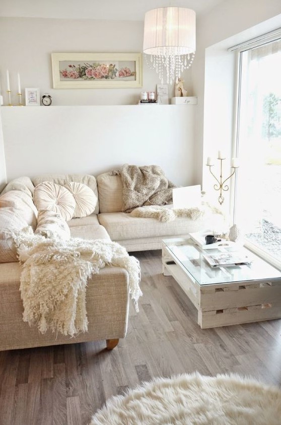 a small, neutral, glamorous living room with a sofa set, a pallet table, a fur rug and a lamp with crystals