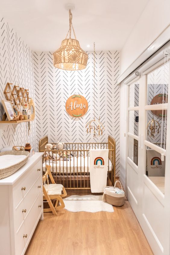 A small boho nursery with accent walls, a metal bed, a white dresser, bookshelves, some furniture and pretty boho decor