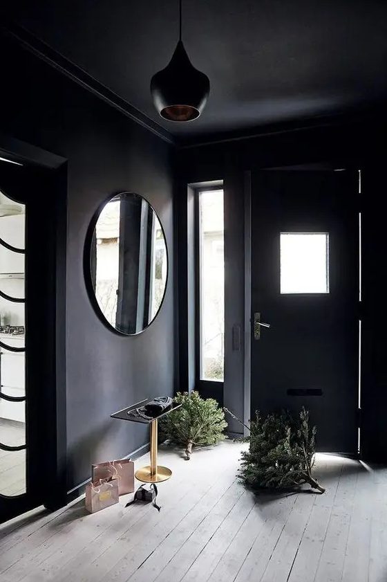 A soot-colored entryway with a round mirror, a table and a beautiful black hanging lamp is fantastic and super chic