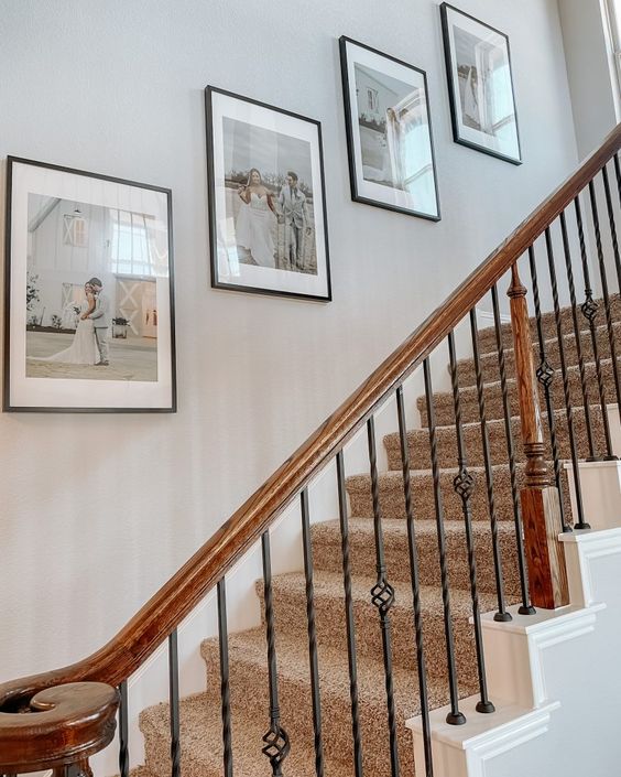 A stylish and laconic gallery wall with wedding photos in matching frames is a cool solution to fill an empty stair wall