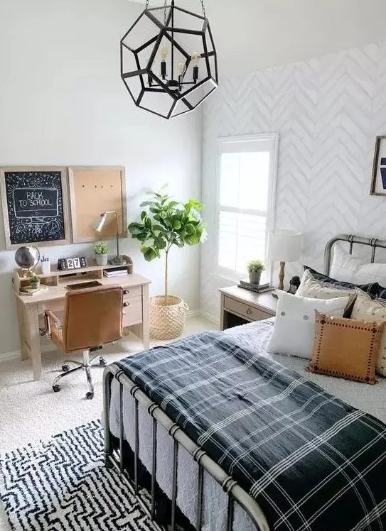 A stylish farmhouse-style teenager's room with a metal bed, lots of pillows, a small desk and a leather armchair, as well as a faceted pendant lamp