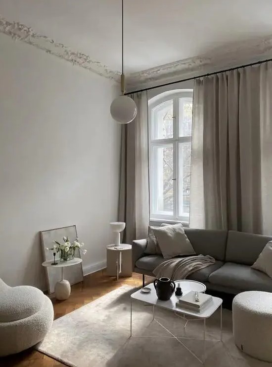 A stylish greige living room with a gray sofa, neutral seating, a light coffee table, some pendant lights and ordinary lamps