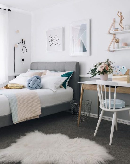 A stylish, modern teenage girl's bedroom with a gallery wall, a gray upholstered bed, a small desk and accents of powder blue, blush and gold