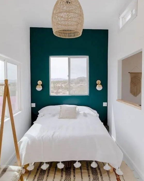 A tiny bedroom that has been enlarged and made inviting with a neutral color scheme, a mirror and multiple windows