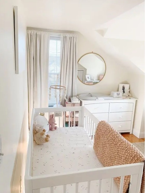 a small children's room in the attic with a white children's bed and a chest of drawers that also serves as a changing table, neutral textiles and a round mirror
