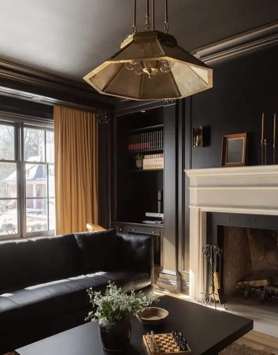 an elegant living room with a fireplace, a black leather sofa, built-in shelves, a coffee table and a chic pendant lamp
