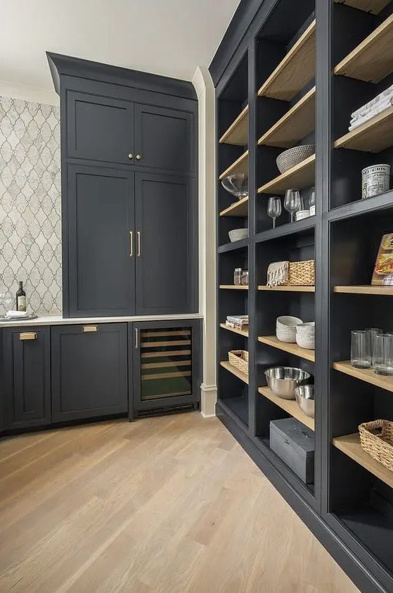 An exquisite soot pantry with built-in cabinets and shelves, gold handles and baskets, and a tiled wall is a beautiful and cool space