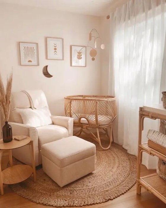 an organic small nursery with a rattan cradle, white chair with footrest, dresser, side table and neutral gallery wall