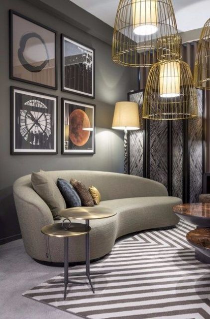 a catchy living room with a retro feel featuring a curved taupe sofa, a statement gallery wall and gold wire hanging lamps
