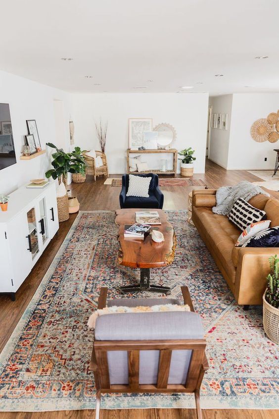 A stylish mid-century modern farmhouse living room with a leather sofa, elegant chairs, a living table and potted plants