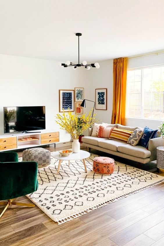 A bright mid-century modern living room with a comfortable sofa, green chair, TV, printed textiles and a bright gallery wall