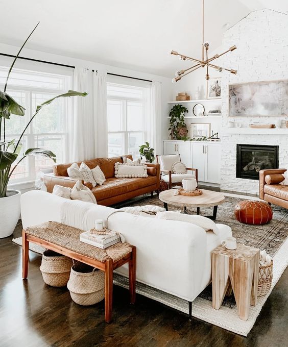 An inviting mid-century modern living room with a built-in fireplace, a white and rust sofa, a wicker bench and potted plants