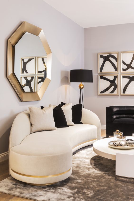 A sophisticated space with a curved white and black sofa, gold accents and eye-catching artwork makes a fantastic living room