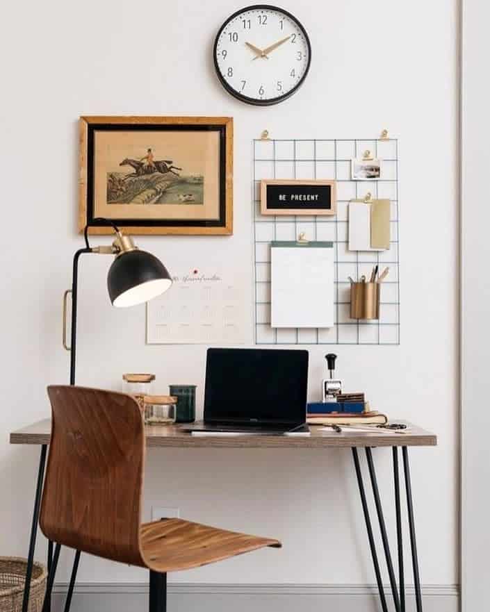Small office space with framed wall art clock and hanging metal grille 