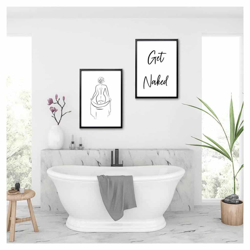 Marble bathroom with white freestanding bathtub and framed wall art