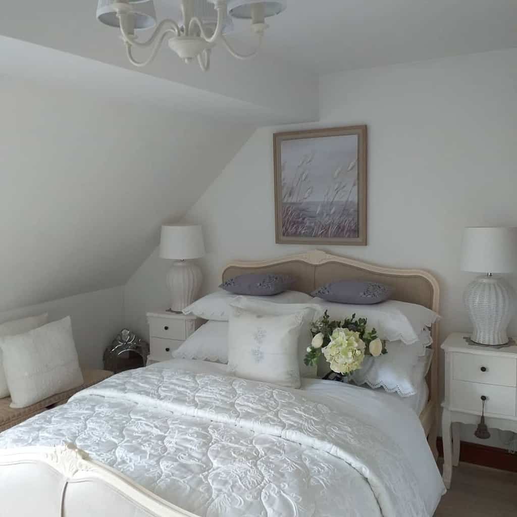 Attic French country bedroom, white bedspread, wicker cabinets, lamps, framed artwork 