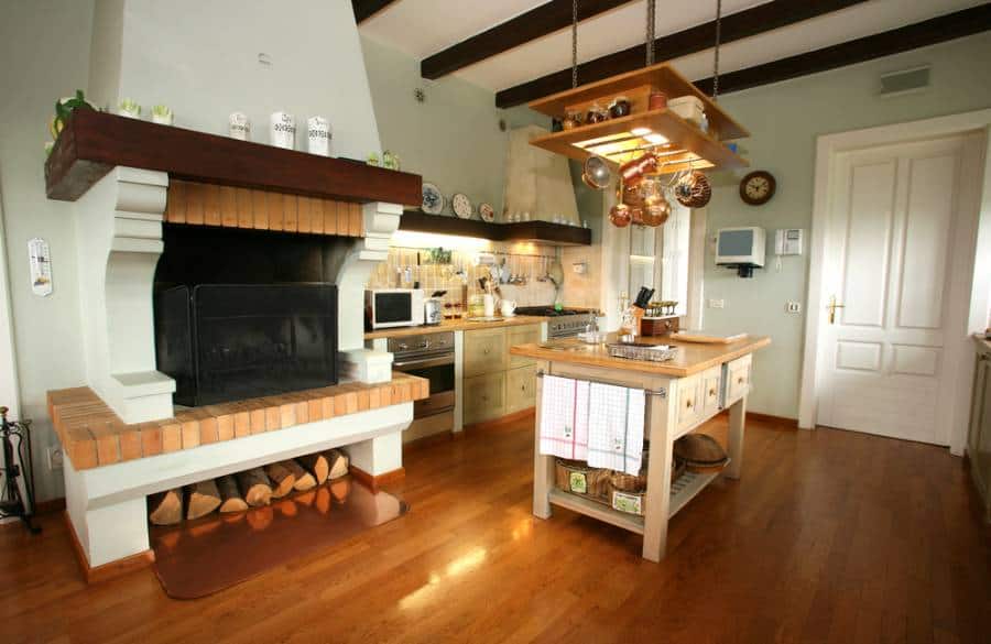 Country style kitchen, copper pots and pans hanging on roof fireplace wood island with drawers