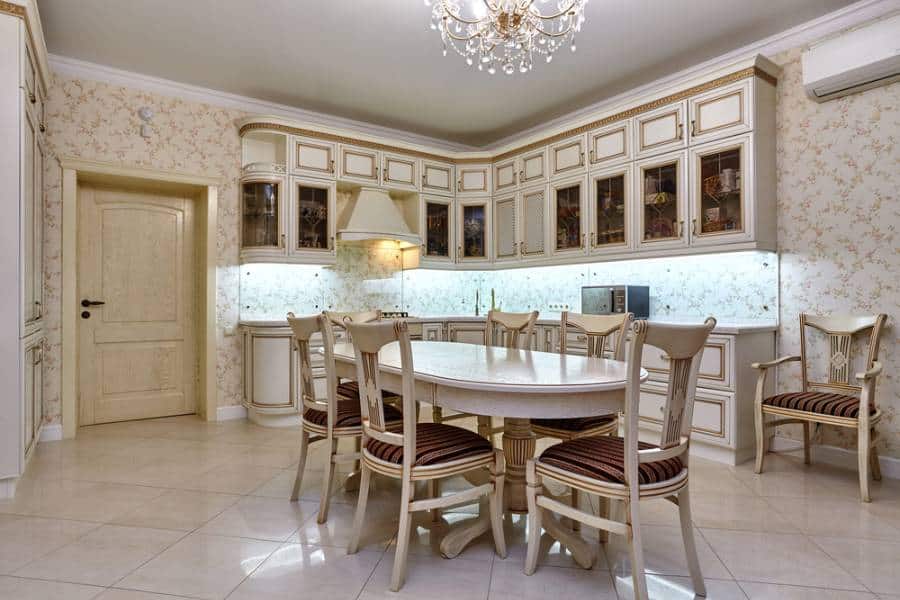 elegant kitchen with tiled floor, round dining table, chandelier, white cabinets 