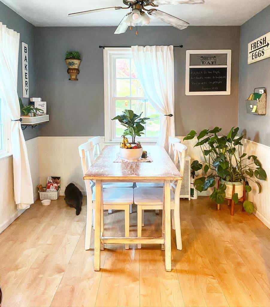 Farmhouse dining room table and four chairs, potted plants, cat