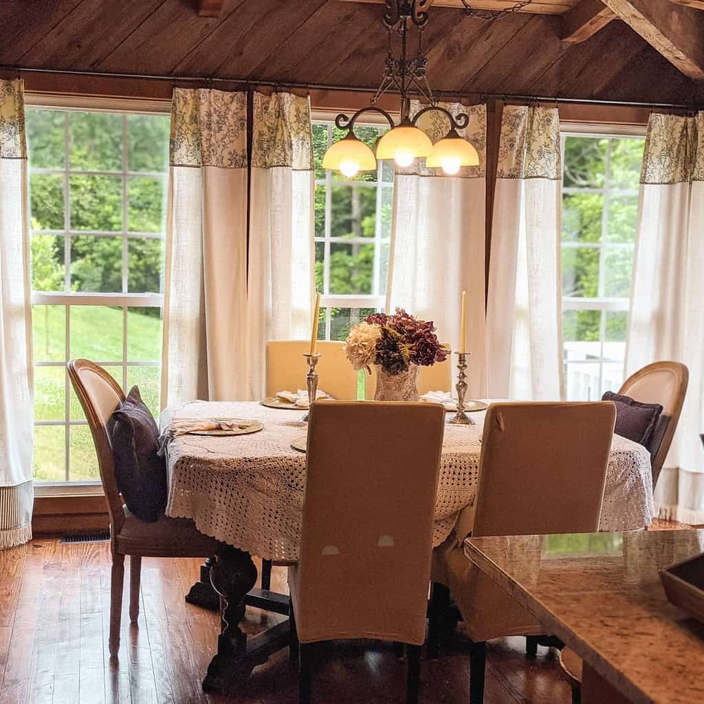 Rustic dining room, vintage tablecloth, white curtains, candles, table, floral arrangement 