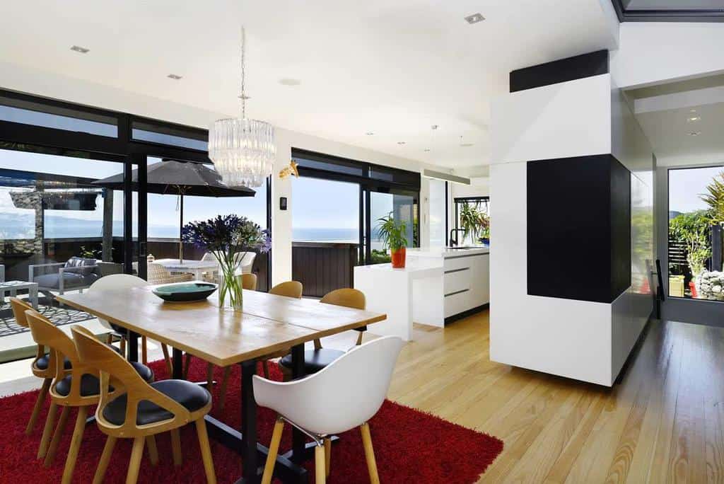 Large modern white dining room and kitchen table with wooden table and red floor carpet 