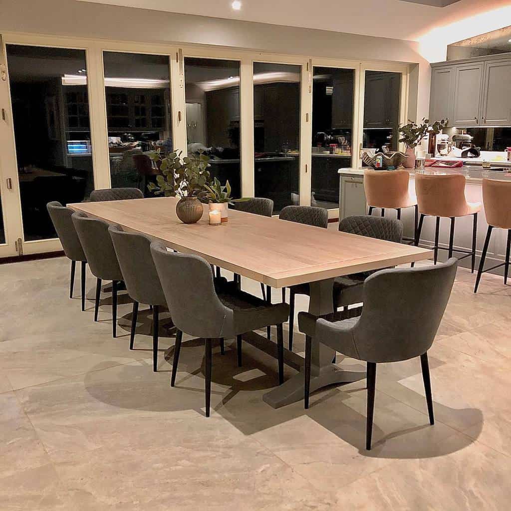 Kitchen, dining room, long dining table with gray chairs, fold-out windows, tiled floor