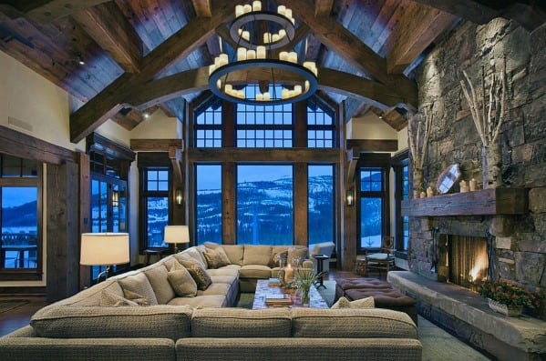 Rustic cabin style living room, huge gray sofa and stone fireplace 