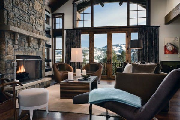 Alpine-style living room with stone fireplace and mountain views