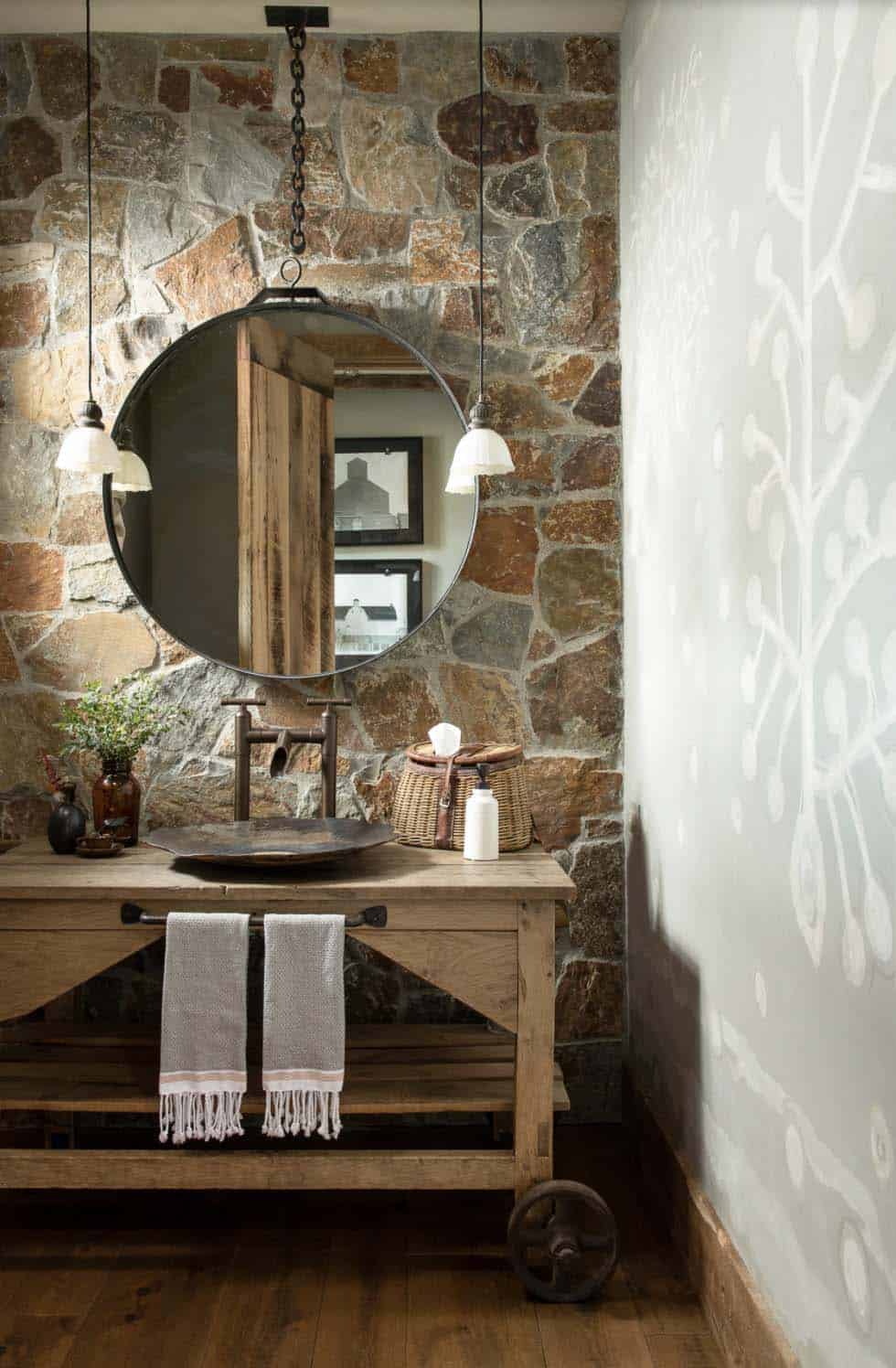 Rustic guest toilet with stone wall and large round mirror