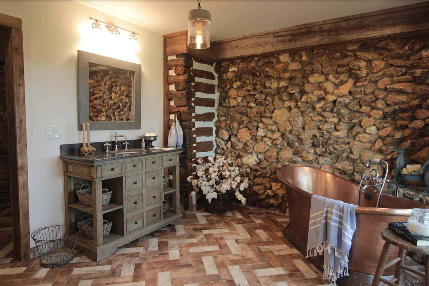 Rustic bathroom with wooden vanity, copper tub and rock wall