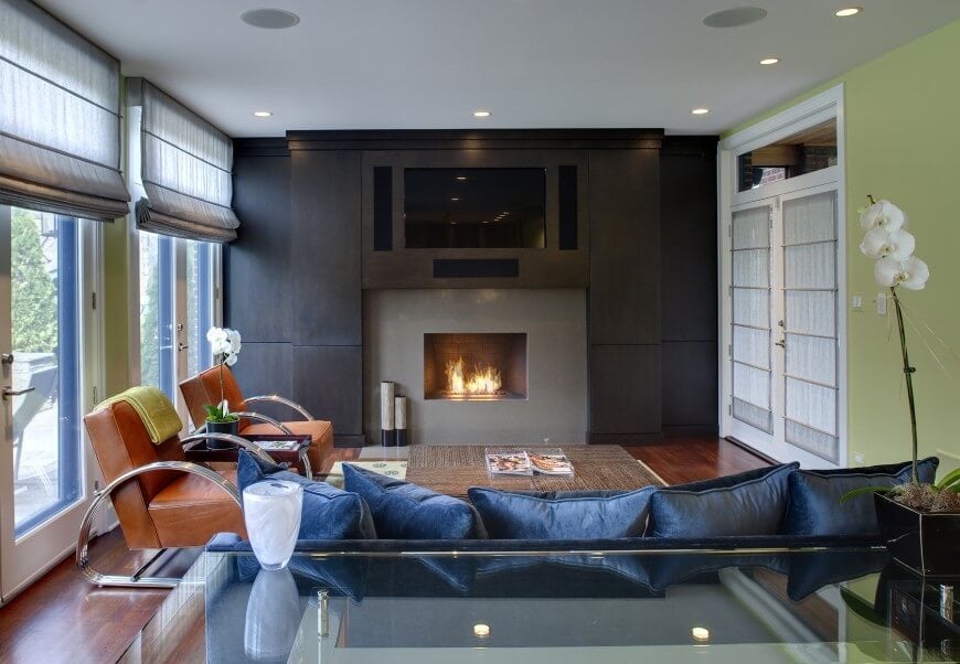Cozy modern family room design with hardwood floors and a wall with custom dark wood paneling framing the gas fireplace.