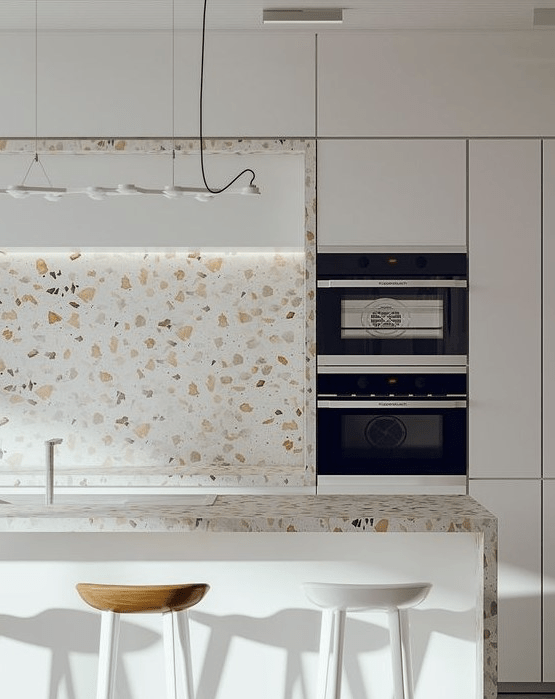 A minimalist white kitchen with cool white terrazzo countertops and a backsplash and a pendant lamp is fantastic