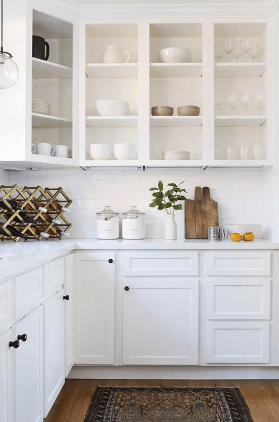 a white farmhouse kitchen with open upper cabinets, a white subway tile backsplash, stone countertops and a wine bottle rack