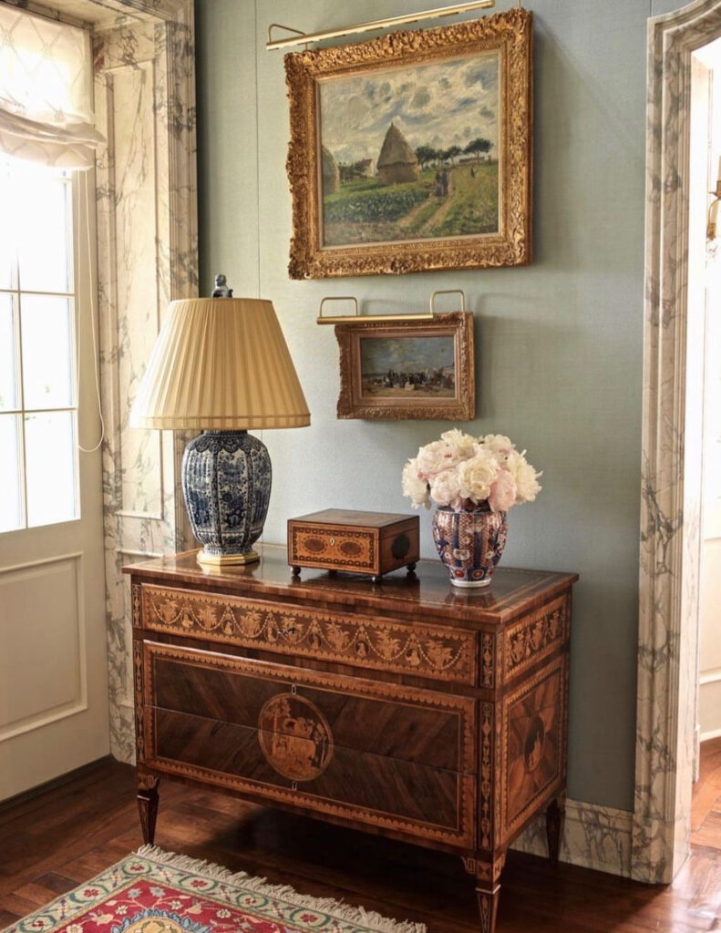 Vintage entry table with ornate lamps and photo frames
