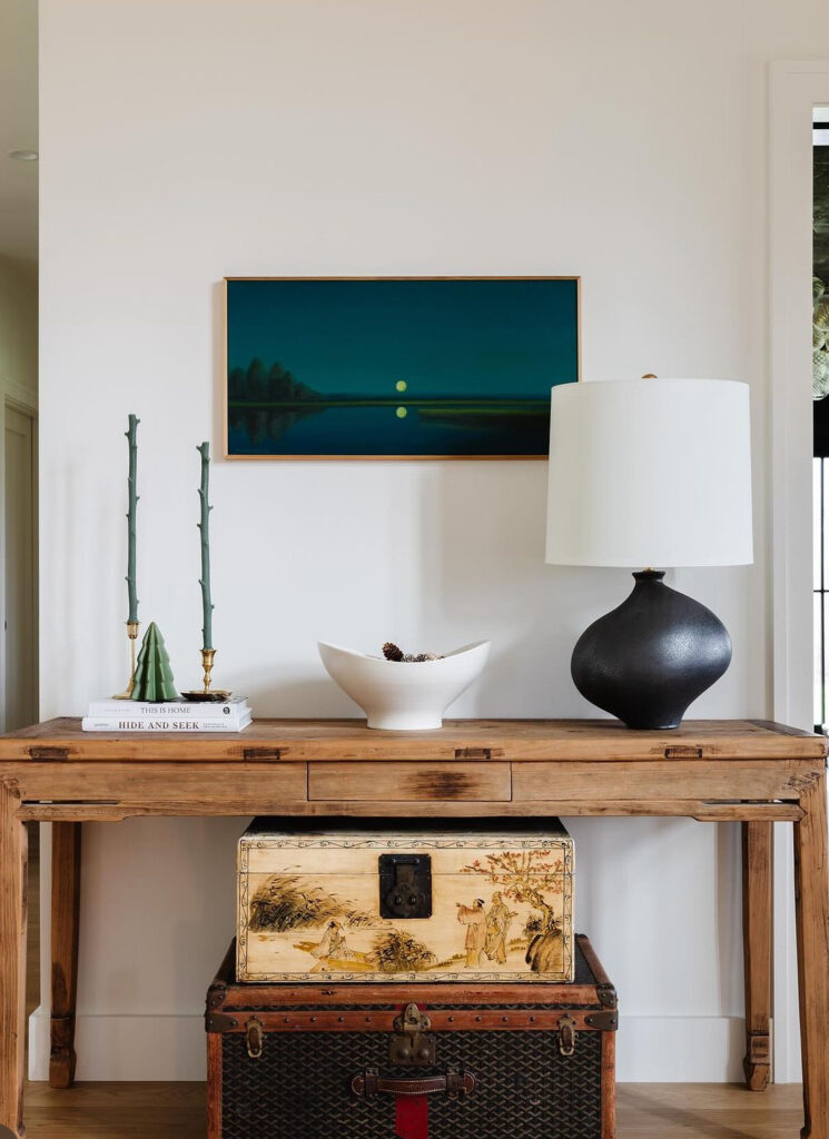Simple entry table with eclectic lamp and atmospheric landscape painting