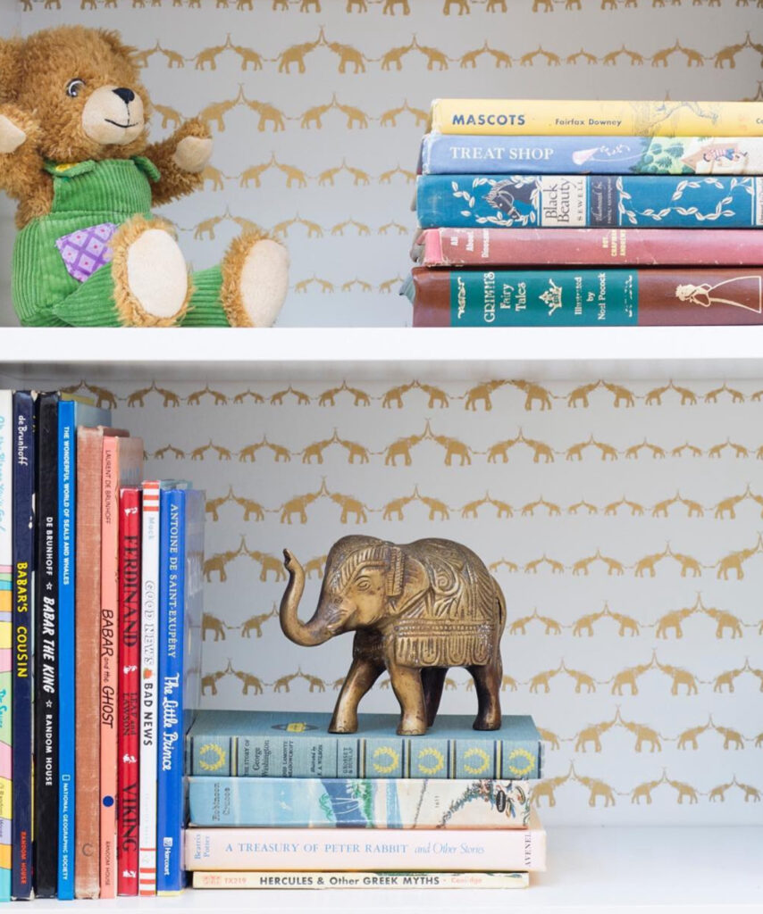 Golden wallpaper with elephant pattern on children's bookshelf