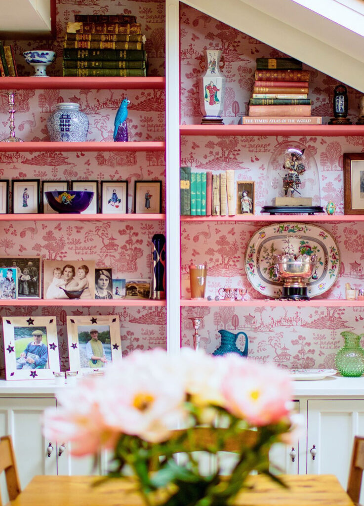Pink toile wallpaper on shelves with painted pink shelves