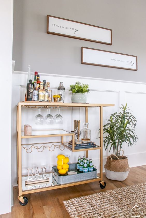 A stylish gold cart with various mirror shelves, stylish with a sign and some lemons in a glass is a very chic idea