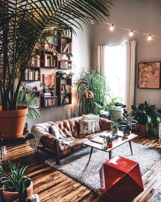 A pretty boho living room with lots of potted plants and succulents, with bright lights overhead and a fiery red faceted side table