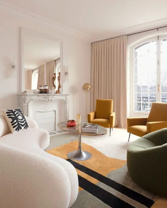 a chic Parisian living room with a non-working fireplace, a curved white bouclé sofa, mustard and green chairs, a coffee table and a mirror above the mantel