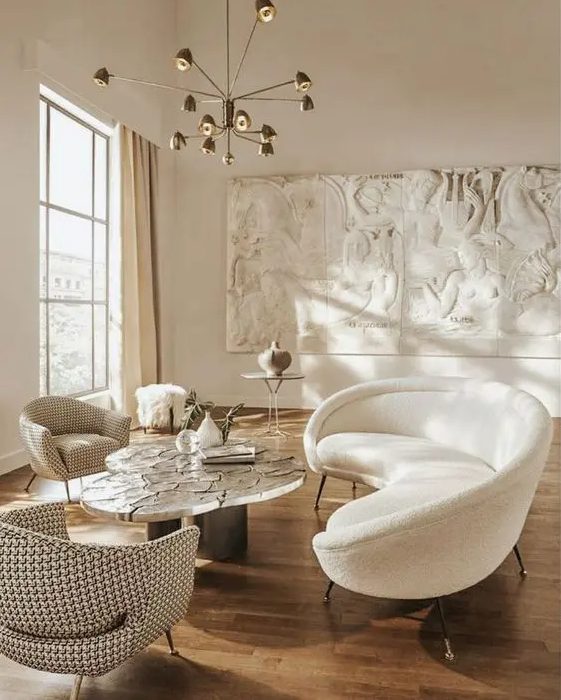 a beautiful and airy living room with unique decor on the wall, a white curved sofa and chairs and a curved coffee table