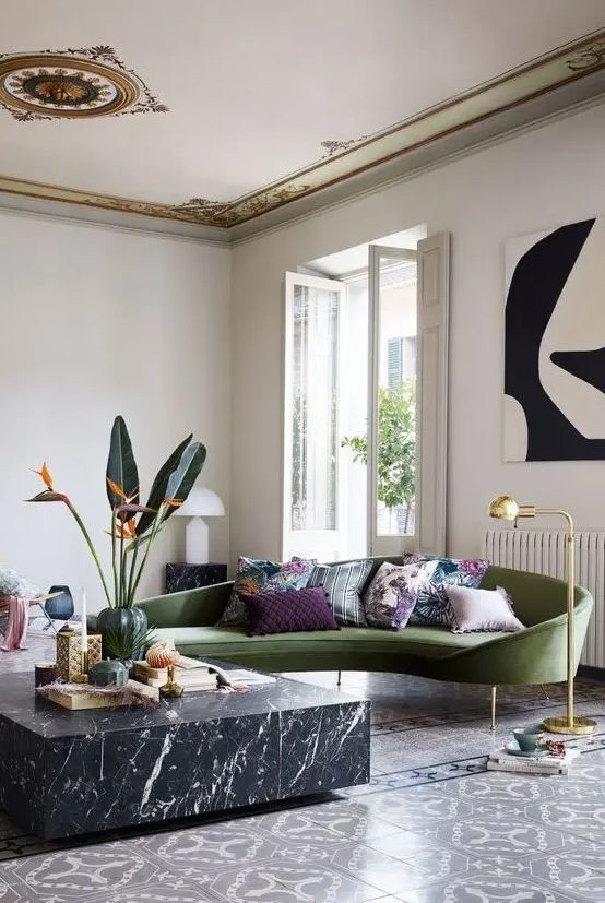 A chic and sophisticated living room with tiles, a black marble coffee table and a chic green curved sofa as the focal point