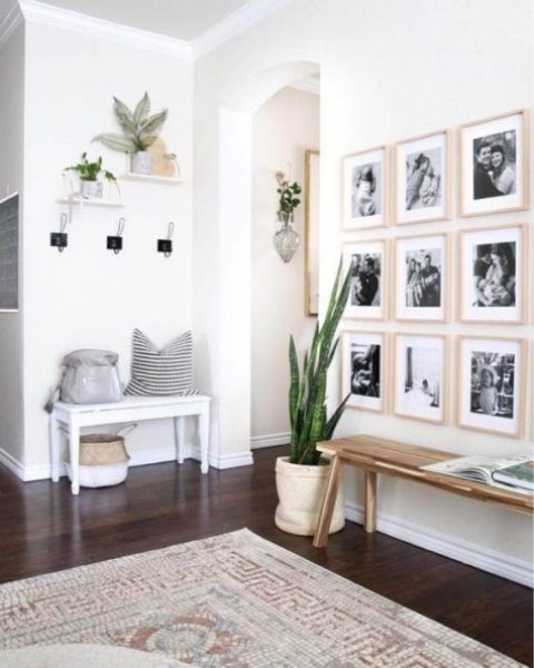 a chic, modern entryway with a few benches, a gallery wall, some plants and clothes racks