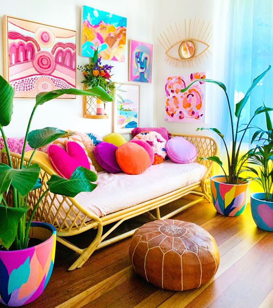 a colorful dopamine living room with a rattan sofa and colorful pillows, a colorful gallery wall, colorful pots and a brown stool