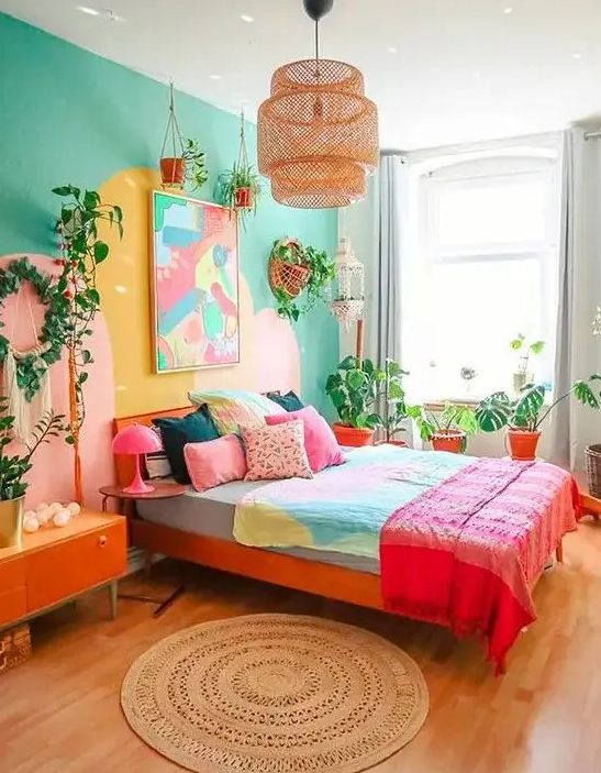 a colorful, eclectic bedroom with an emerald green accent wall, a red bed with colorful linens, bright artwork, potted plants and an orange credenza