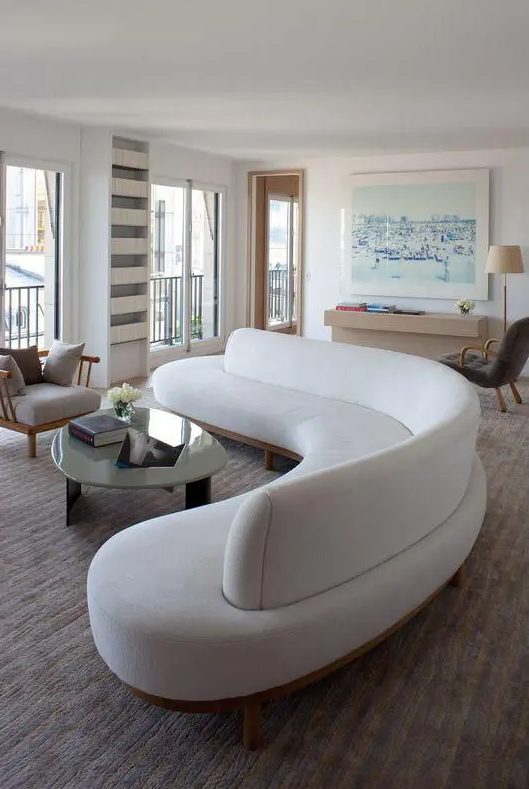 A curved white couch makes a stylish statement in the living room while separating the zones of the room