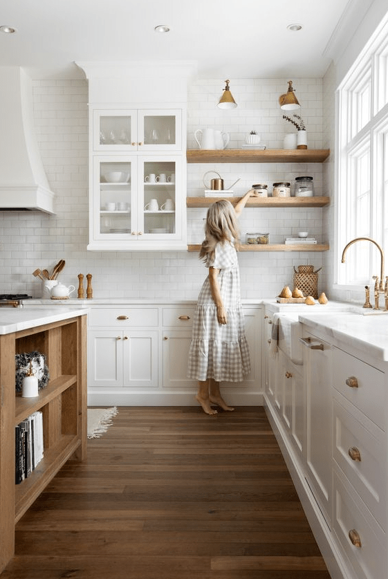 a delicate cream kitchen with marquetry and glass cabinets, open shelving, white quartz countertops, stained shelves and a stained kitchen island