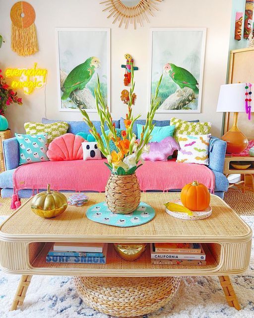 A living room with dopamine decor, a blue sofa and colorful pillows, a cane coffee table, statement decor and artwork