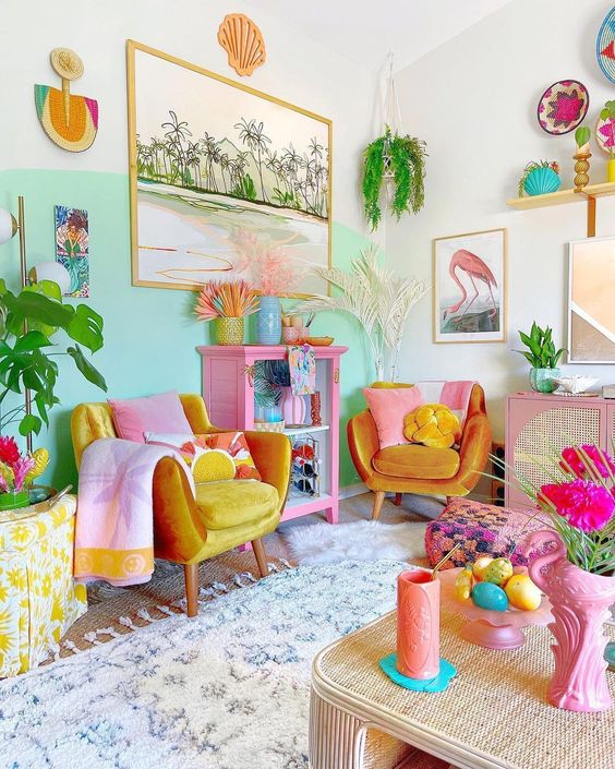 A dopamine decor living room with a bold aqua accent wall, marigold chairs, colorful textiles, greenery and bright decor